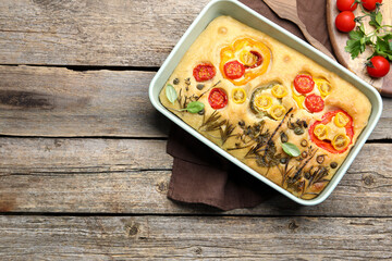 Delicious focaccia with flowers made of vegetables on wooden table, top view. Space for text
