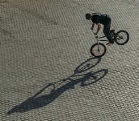 Balancing BMX Bike Trick on Sunny Pavement