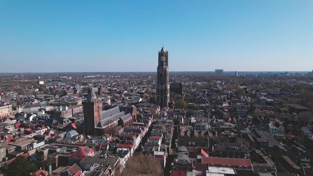 Aerial of Dutch city Utrecht with cathedral tower and church rising above the cityscape of the old historic center against a blue sky
