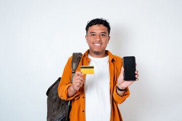 Image of handsome young Asian student holding mobile phone, credit card and using backpack on...