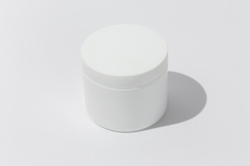 White Cosmetic Cream Jar. Cylinder on textured tan paper with shadows