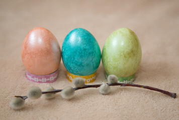 Dyed chicken eggs and a sprig of willow lay on a beige background.