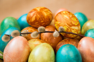 Dyed chicken eggs and a sprig of willow lay on a beige background.