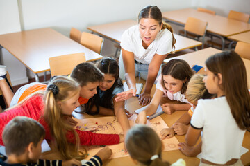 Teacher and schoolchildren play a table game in school class