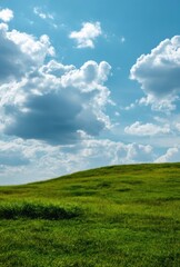 Fototapeta premium Green Grass Hill with Clouds in the Blue Sky on a Sunny Day