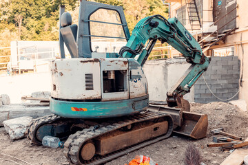 Small excavator parked on construction site after premature floor finishing