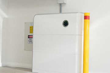 16Kw Solar battery home storage unit in a garage with yellow safety bollard and warning signs