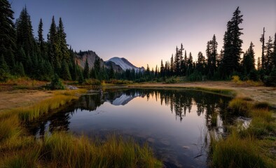 Obraz premium Reflecting Mountain in Calm Lake Surrounded by Forest at Sunset
