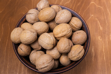 a lot of walnuts are in pottery on a wooden brown table
