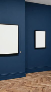 Two framed blank canvases on dark blue wall in a modern art gallery, oak wood parquet flooring, contemporary interior, clean aesthetic