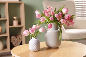 Beautiful tulips in vases on coffee table indoors