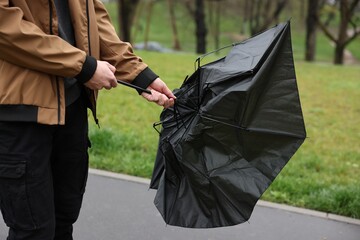Man with broken umbrella fighting wind under rain outdoors, closeup