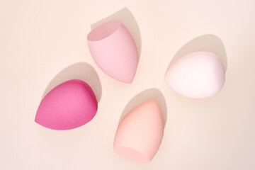 Makeup sponges arranged artfully on a beige background
