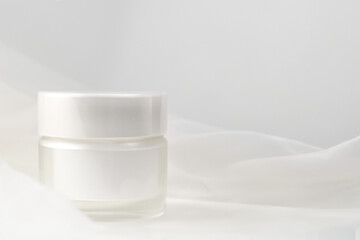 Minimal white cosmetic jar on soft fabric background