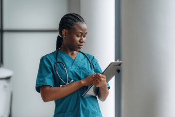 Stethoscope is on the neck. Female doctor is indoors in modern room