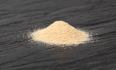 Garlic powder pile, dried granulated chopped crushed garlic cloves, cut into small pieces