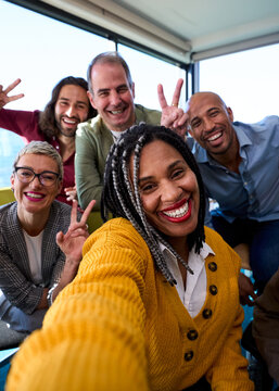 Vertical Selfie of a group of happy multiracial business people taking photo with a phone in the office
