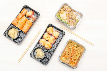 Fish sushi rolls with salmon,noodles,salad packed in disposable food container box.Seafood,Food delivery,take out service from restaurant concept