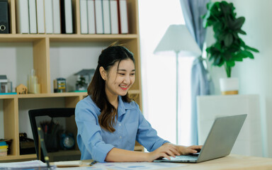 An Asian woman employee focused on completing the monthly sales summary with dedication.