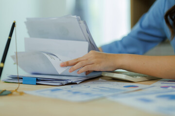 An Asian woman employee focused on completing the monthly sales summary with dedication.