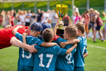 Group of soccer boys rising golden trophy after winning school football tournament. Happy children...