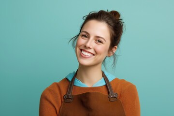 Smiling woman in casual brown apron against  teal background
