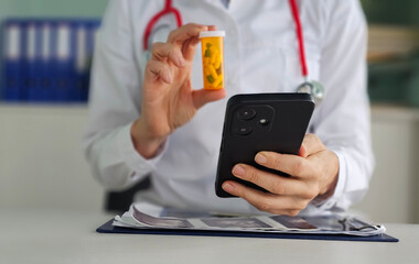 Doctor checking prescription details while holding medication bottle and smartphone