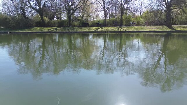 Drone view of a beautiful park and water pond in Brussels in a calm spring maring close to surface