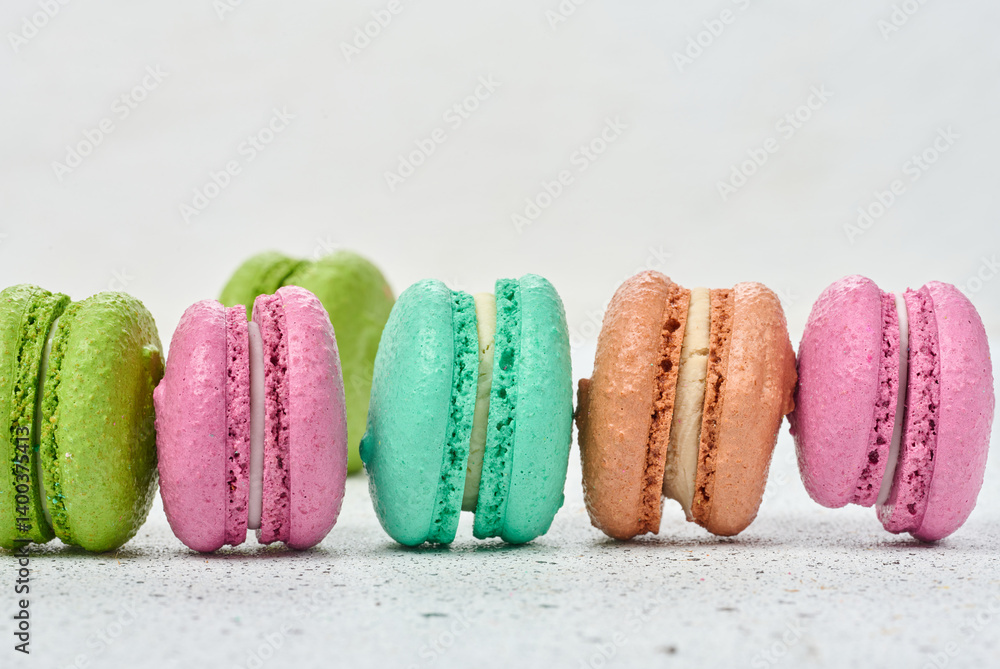 Poster an assortment of colorful macarons on a white surface with dark speckles. the macarons have a smooth