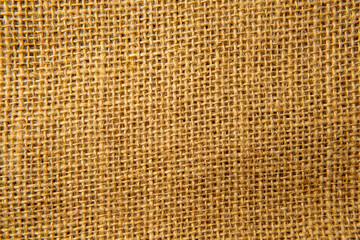 A tightly framed, top-down shot showcases the rough texture of burlap fabric. The coarse, woven...