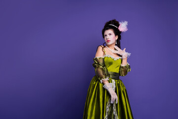 Elegant woman in green historic costume with purple background showcasing baroque style and royal...