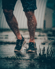 A runner's feet in dirty puddle with water splashe. Rainy day sport activities 