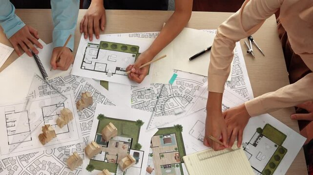 Architect and safety engineer discussion about building construction use blueprint on table with architectural document, measurement tool and wooden block scatter around at modern office. Delineation.