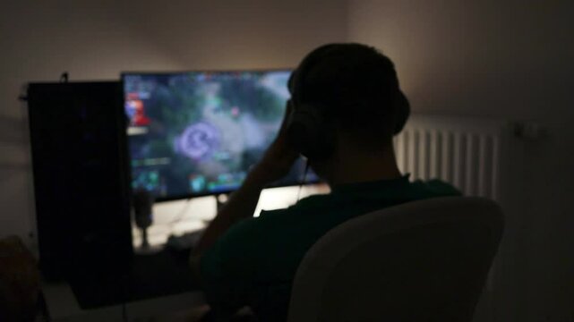 Selective focus on Caucasian gamer using gaming pc professional setup while having fun playing online games at home. Man enjoying relaxing free time streaming multiplayer competition.