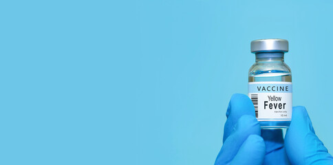 Doctor wearing protective gloves holding a Yellow Fever vaccine bottle, symbolizing modern healthcare, disease prevention, scientific research, immunization, vaccination awareness. Banner, copy space
