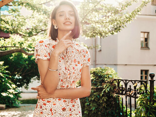 Naklejka premium Portrait of young beautiful smiling woman in trendy summer sundress. Sexy carefree woman posing on the street background at sunset. Positive model outdoors