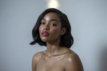 Obraz premium Close-up portrait of beautiful African American woman with glowing skin applying skincare serum or clay mask – black beauty, melanin skin, facial care, wellness, isolated on white background