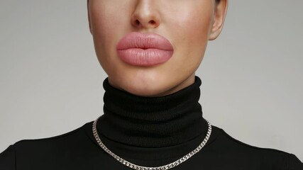 Woman with dramatic full lips and silver chain in a black turtleneck video footage. Female fashion model in studio clip for beauty and lifestyle content. - Powered by Adobe