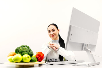 Female nutritionist working in a modern clinic on a light background at a computer near fresh...