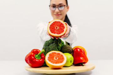 A young female nutritionist points out fresh fruits and vegetables. Broccoli, apple, avocado,...