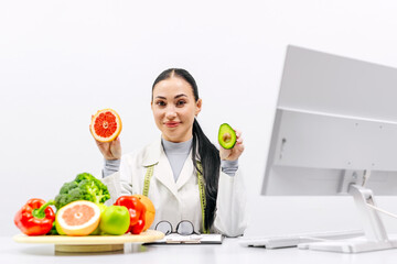 A young female nutritionist points out fresh fruits and vegetables. Broccoli, apple, avocado,...