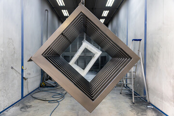 Pièce métallique suspendue par des câbles dans un entrepôt, en cours de traitement de...