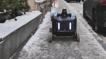 Autonomous delivery robot moving on a snowy sidewalk in Moscow.