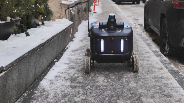 Autonomous delivery robot moving on a snowy sidewalk in Moscow.