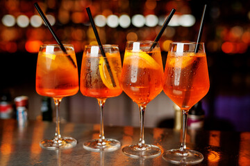 Aperol Spritz cocktails served in elegant wine glasses on a bar counter, garnished with fresh orange slices.