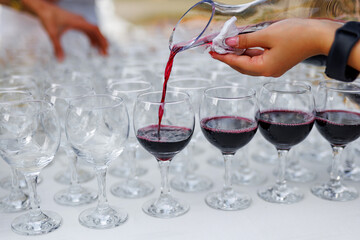 A person is pouring red wine into a glass using the decanter