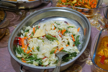 A vibrant dish of mixed vegetables including cabbage, soon, long beans, and carrots, cooked in a light coconut milk sauce, showcasing a creamy and flavorful Southeast Asian culinary tradition.