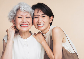 アジア人母娘ポートレート。彼女たちは寄り添い笑っている。	