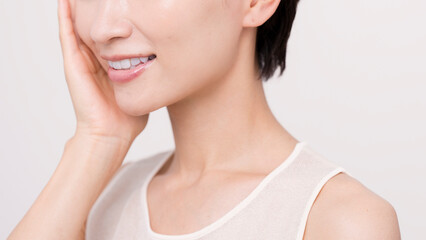 片手で頬を触っているアジア人女性。スキンケア。