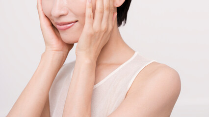 両手で頬を触っているアジア人女性。スキンケア。